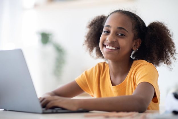 Non-Verbal Communication Skills for Children with Autism girl smiling while on a laptop