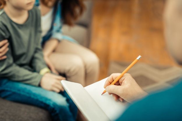 What Are Repetitive Behaviors in Autism therapist talking to a mother and her child with ASD and explaining what are repetitive behaviors in autism