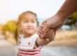 small female child being taken by the hand by caring adult who is identifying non verbal autism in children