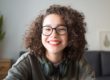 smiling young woman with glasses asking neurotypical vs. neurodivergent what's the difference