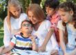 mother in park on a sunny day surrounded by children experiencing talking to your child about having a sibling with autism