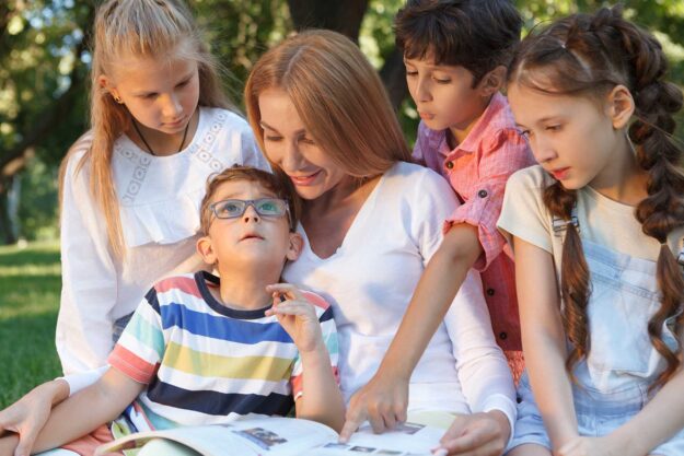 Talking to Your Child About Having a Sibling With Autism mother in park on a sunny day surrounded by children experiencing talking to your child about having a sibling with autism