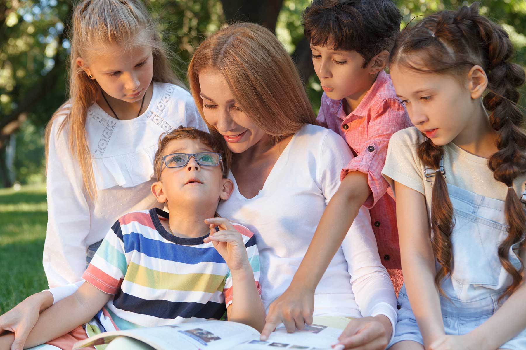 mother in park on a sunny day surrounded by children experiencing talking to your child about having a sibling with autism